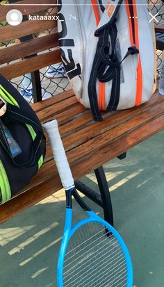 a blue tennis racket sitting on top of a wooden bench next to a duffel bag