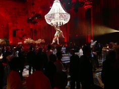 a group of people standing around a room with chandelier hanging from the ceiling