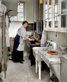 a woman in an old fashioned kitchen cooking food