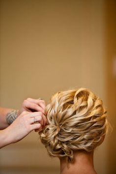 a woman is getting her hair done by another person with red nails and a ring on her finger