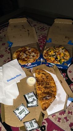 three pizzas sitting on top of cardboard boxes next to a candle and some napkins