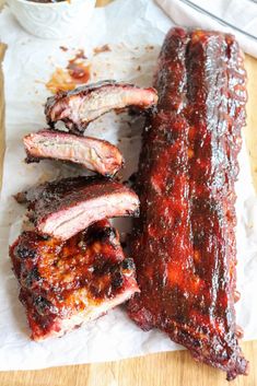 barbecue ribs are sitting on wax paper next to a cup