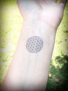 a person's arm with a flower of life tattoo on the left side of their arm