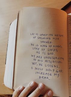 a hand holding an open book with writing on it