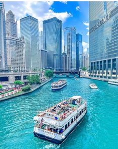 several boats are traveling down the river in front of some tall buildings and skyscrapers