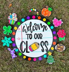 a sign that says welcome to our class surrounded by magnets and paper clips on the grass