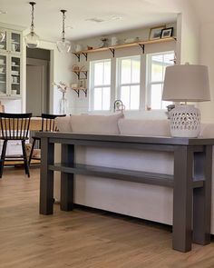 a living room filled with furniture next to a dining room table and two lamps on top of it