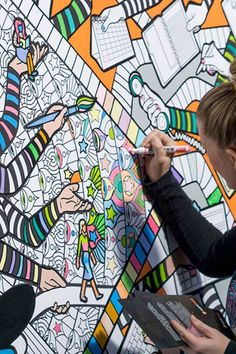 a woman is drawing on a large mural