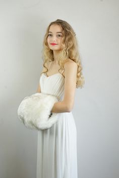 a woman in a white dress holding a fur purse