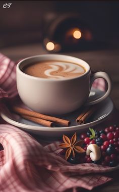 there is a cup of coffee with cinnamons on the saucer and berries around it