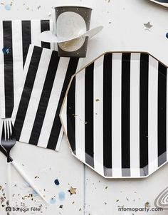 black and white striped paper plates with silverware on the side, next to each other