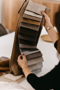 a woman is holding up some fabric samples