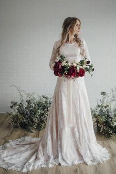 a woman in a wedding dress holding a bouquet of flowers and looking off into the distance