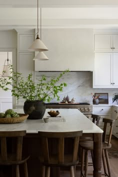 a kitchen with white cabinets and an island in the center surrounded by wooden stools