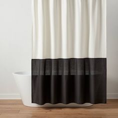 a shower curtain with black and white stripes on the bottom, along with a bathtub