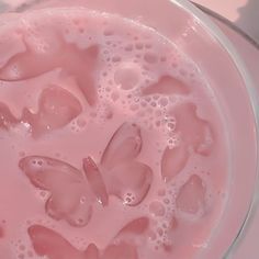 pink liquid in a glass bowl with butterflies on the bottom and bubbles around it's edges