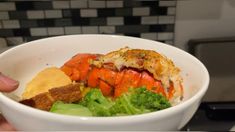 a person holding a bowl filled with seafood and broccoli on the counter top