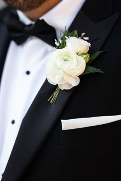 a man wearing a black tuxedo with white flowers on it's lapel