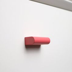 a close up of a pink object on a white surface with a metal bar attached to it