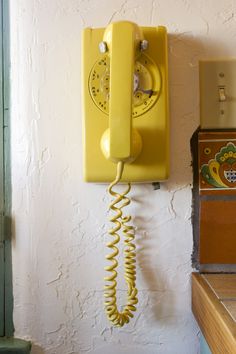 an old yellow phone is hanging on the wall