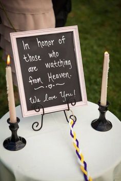 a sign that is on top of a table with two candles in front of it