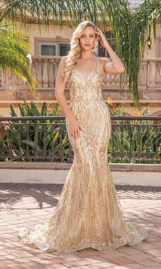 a woman in a gold gown posing for the camera with her hand on her head