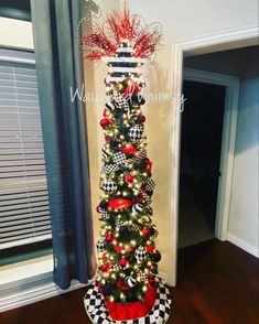 a christmas tree decorated with red, white and black ornaments is in the corner of a room