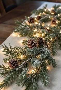 christmas garland with pine cones and lights on a white table cloth covered in snowflakes