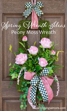 a wreath with pink flowers and green leaves hanging on the front door to say spring wishes