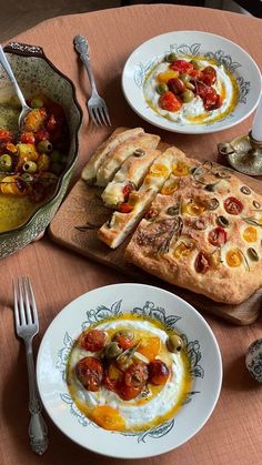 two plates with food on them sitting on a table next to silverware and utensils