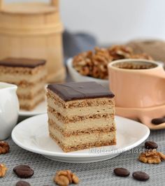 a piece of cake sitting on top of a white plate next to a cup of coffee