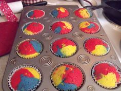 cupcakes with red, yellow and blue frosting in a muffin tin