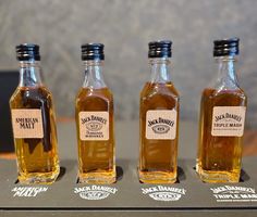 three bottles of maple syrup are lined up on a table with labels in front of them