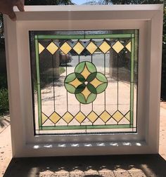 a hand holding up a stained glass window in front of some palm tree's