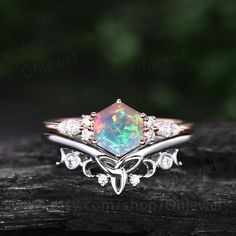 an opal and diamond ring on top of a piece of wood