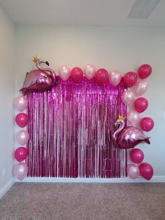 balloons and streamers are hanging from the wall in front of a pink flamingo backdrop