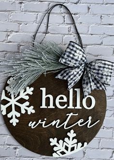 a wooden sign that says hello winter with snowflakes on it and a bow