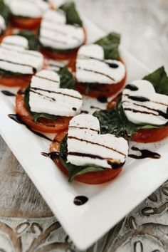 small tomatoes with mozzarella and spinach leaves on a white square platter