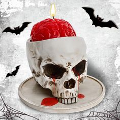 a skull with a red candle in it's head on top of a plate