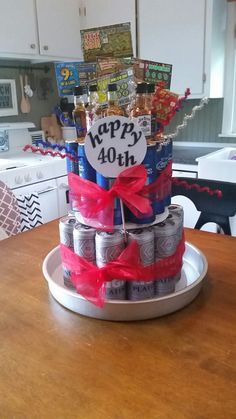 a birthday cake made out of cans and wrapped in red ribbon on top of a wooden table