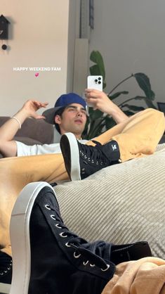 a young man laying on top of a couch holding a cell phone in his hand