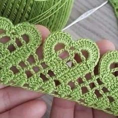 crocheted hearts are being held by someone's hand with yarn in the background