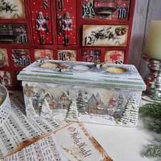 a christmas card box sitting on top of a table next to music sheets and candles