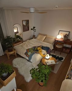 a bedroom with a bed, desk and plants on the floor in front of it