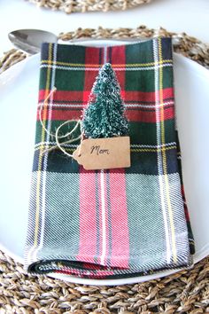 a plaid napkin with a small christmas tree on it is sitting on a white plate