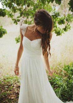 a woman in a white dress is walking through the grass