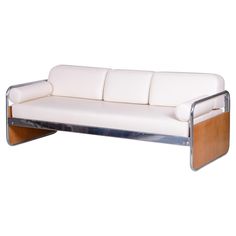 a white leather couch with wood trim on the armrests and back rests against a white background