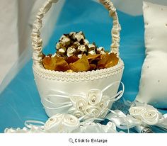 a white basket filled with lots of flowers on top of a blue table next to pillows