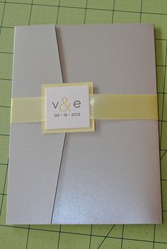 a wedding guest book with a yellow ribbon on the front and side, sitting on top of a cutting board