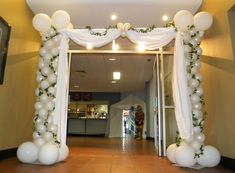 an entrance decorated with white balloons and greenery